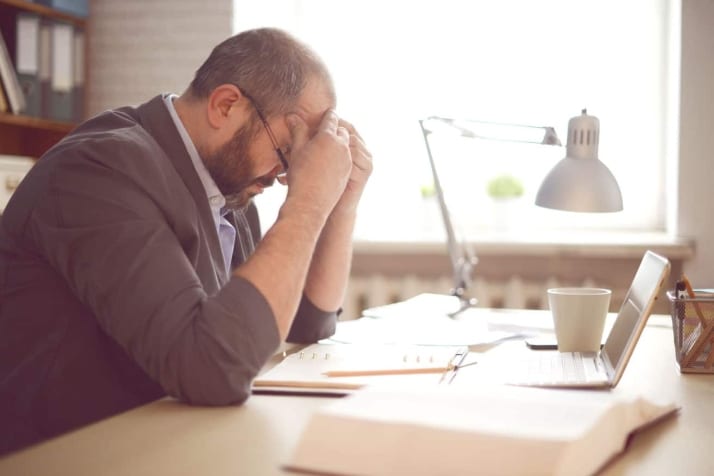 A man looking frustrated at his desk