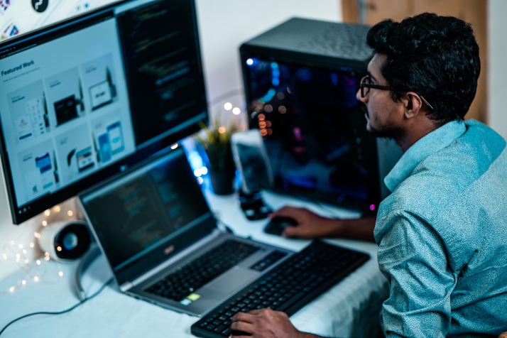 A man working on a lap top and another monitor computer.